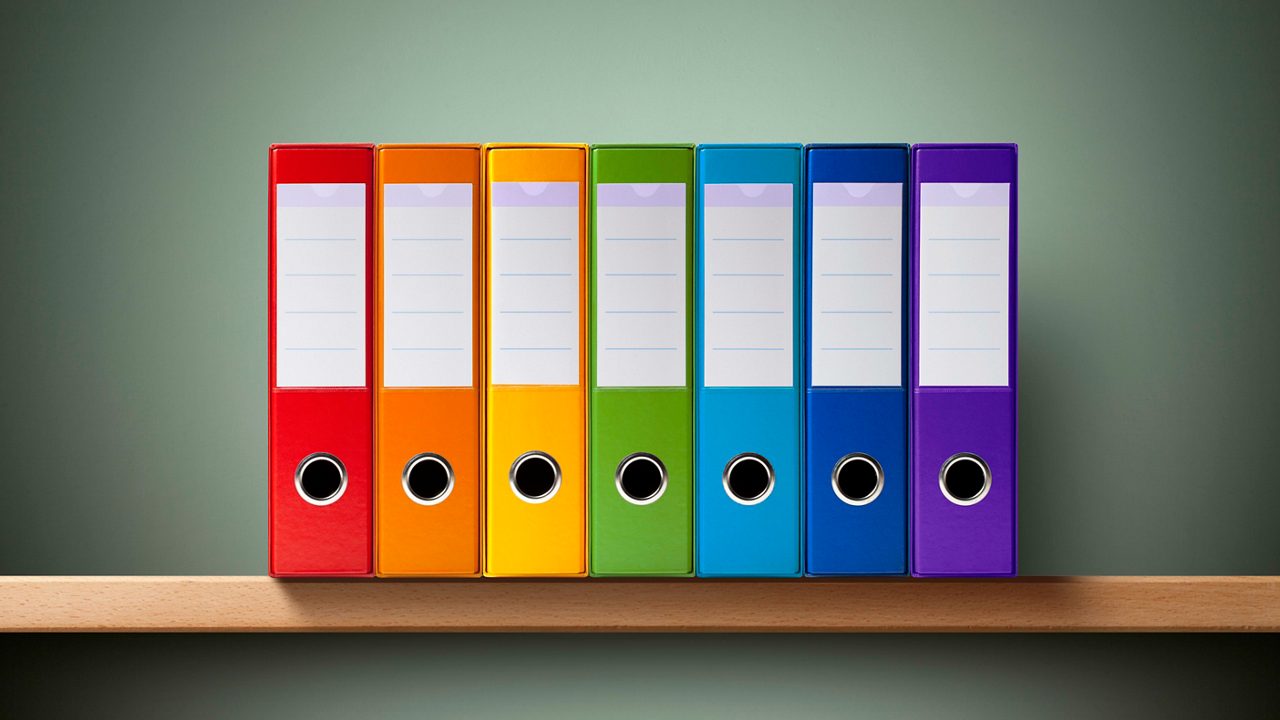 A stack of colorful binders on a shelf.