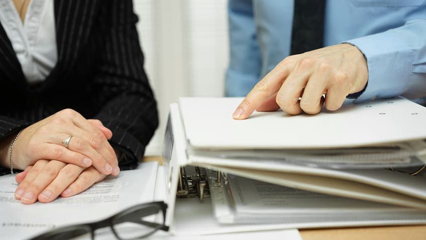 A businessman and woman pointing at a folder.
