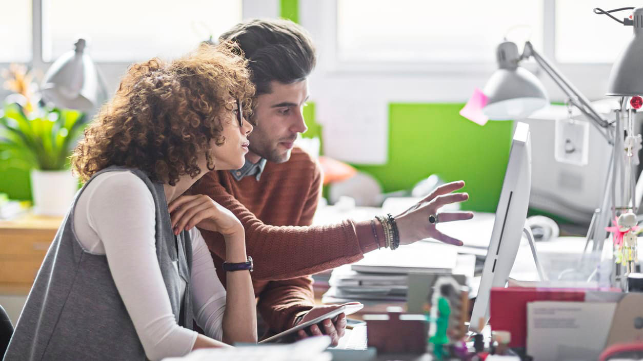 A man and woman looking at a computer screen.