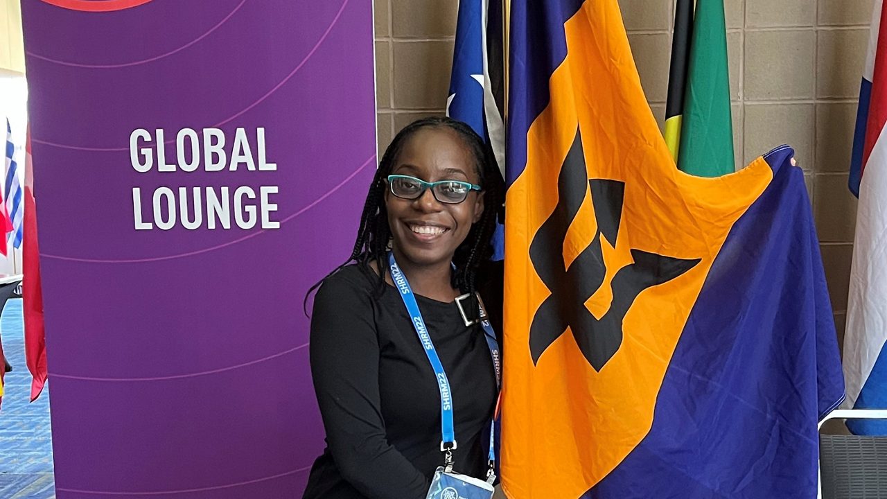 A woman standing next to a flag in a conference room.