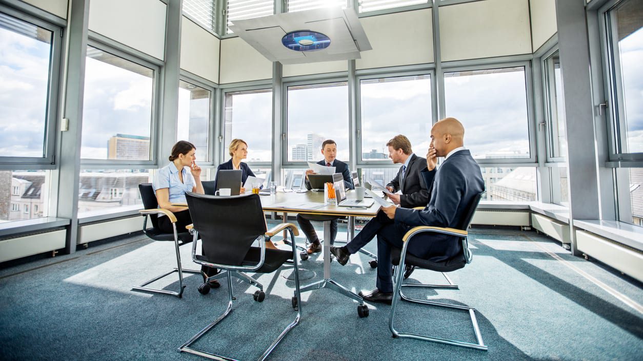 A group of business people sitting around a table in a conference room.