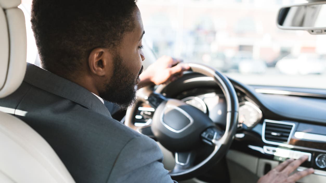 A man in a suit sitting in the driver's seat of a car.