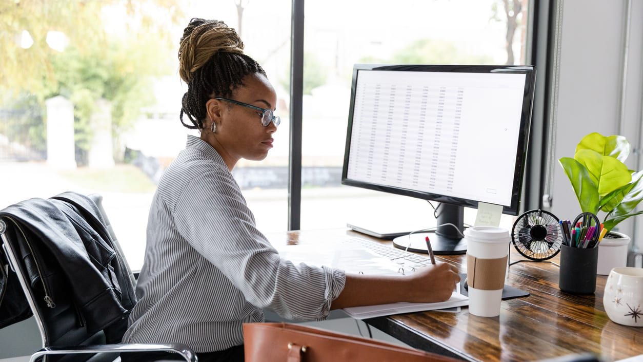 A woman working at a desk in front of a computer.