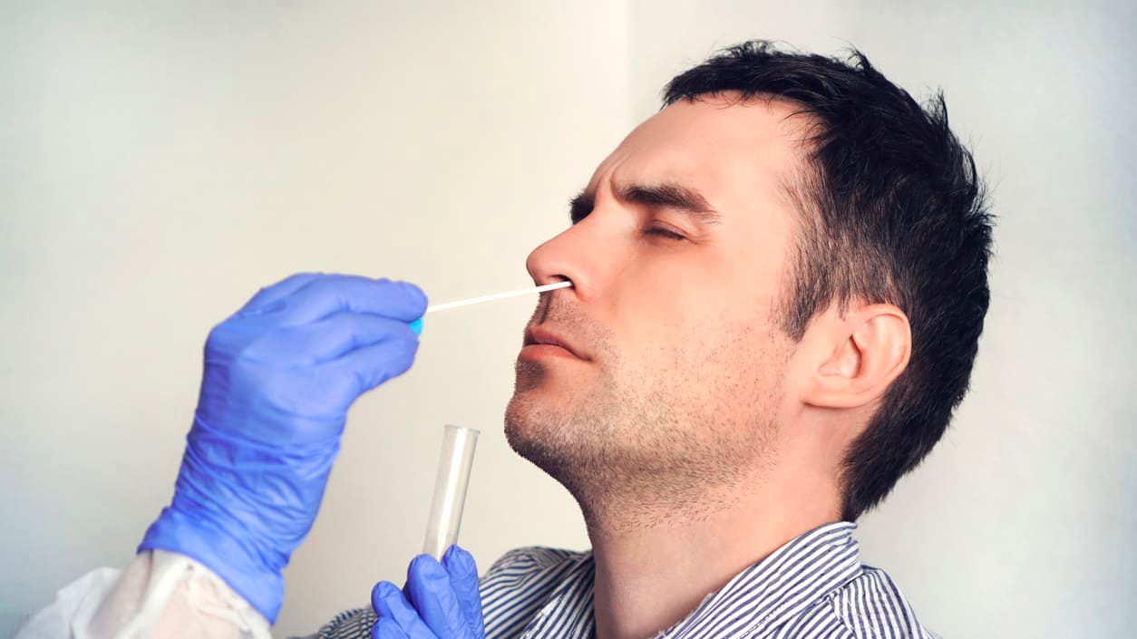 A man is getting his nose swabbed by a doctor.