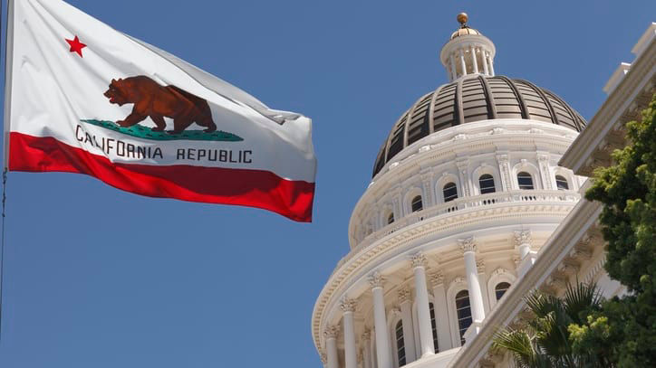 A california flag flies in front of the california capitol building.