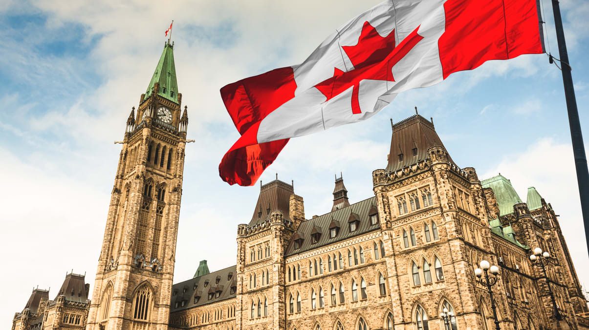 A canadian flag flies in front of a building.