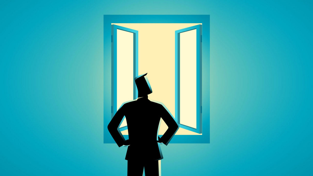 A silhouette of a man looking out of an open window.