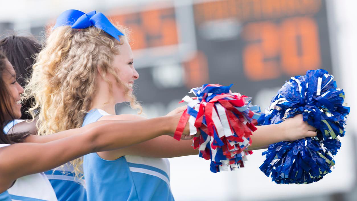 Cheerleaders holding pom poms during a football game.