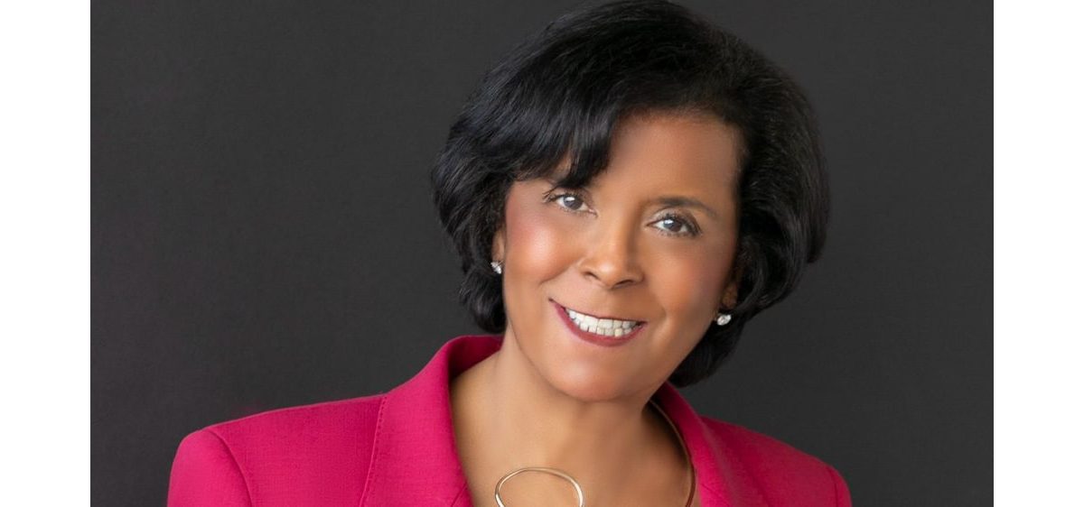 A woman in a pink suit posing for a photo.