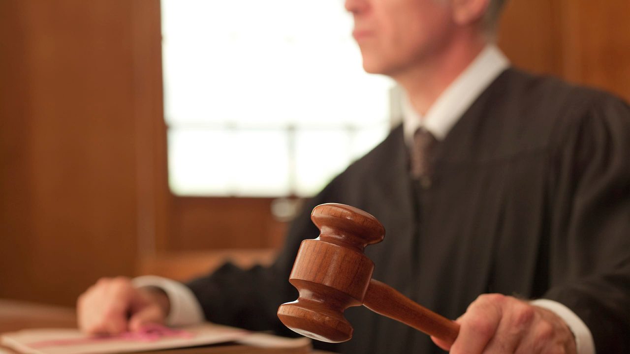 A judge holding a gavel in a courtroom.