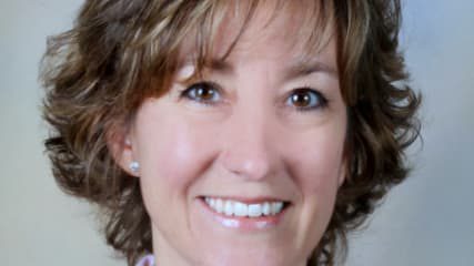 A woman in a business suit smiles for the camera.