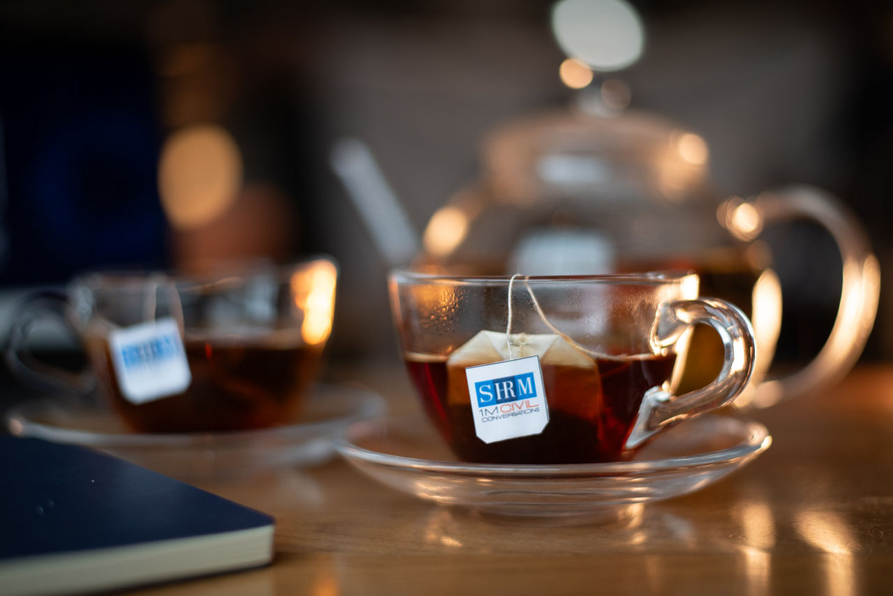 A cup of tea with a tea bag labelled SHRM, 1M Civil Conversations