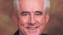 An older man in a black jacket and white shirt.