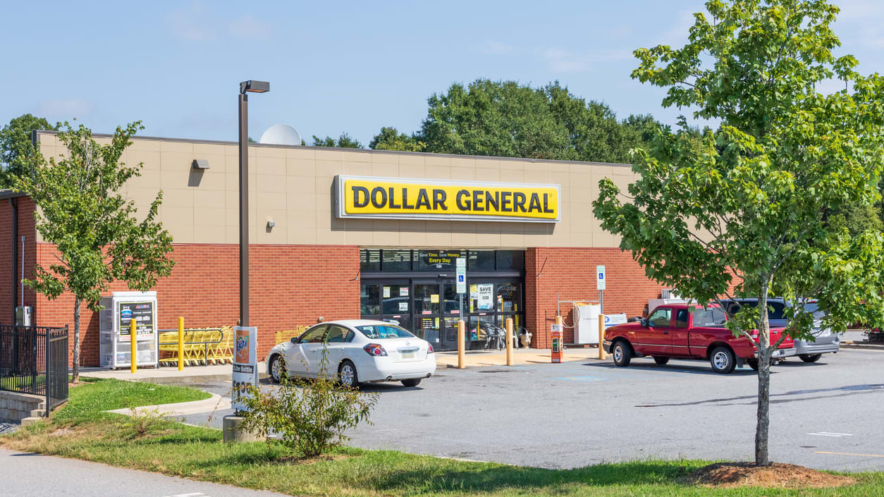 A dollar general store with cars parked in front of it.