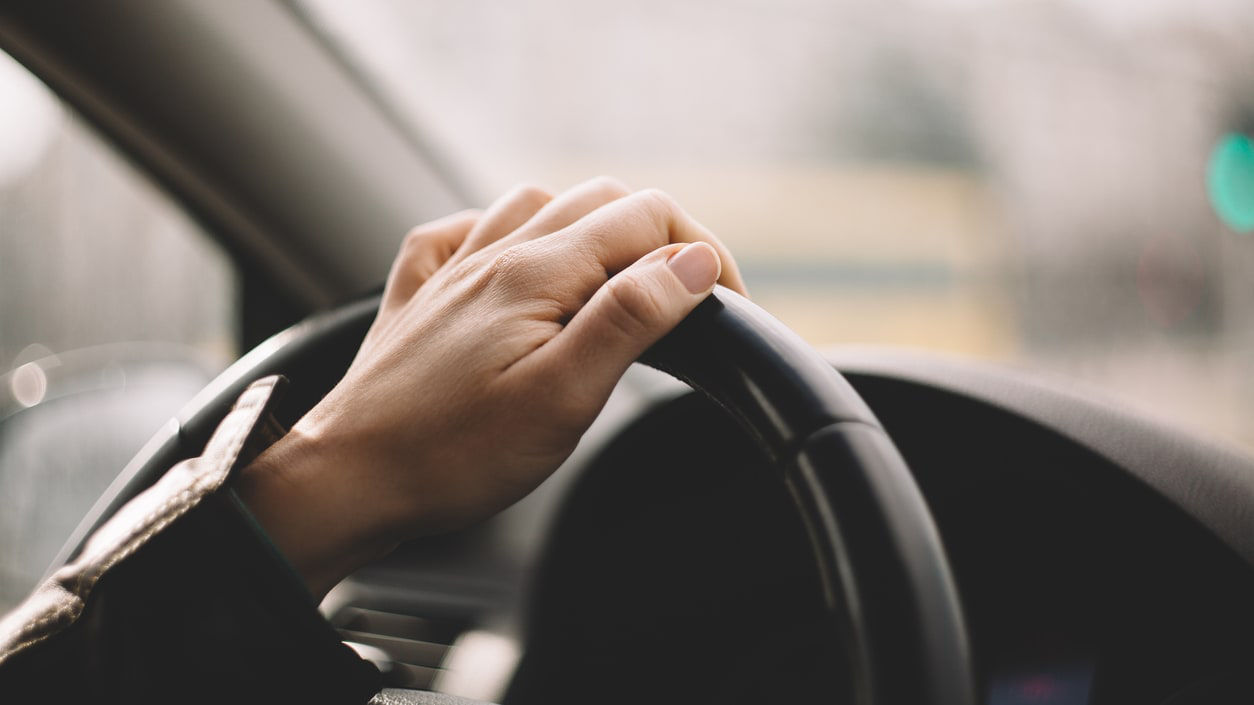 A woman's hand on the steering wheel of a car.