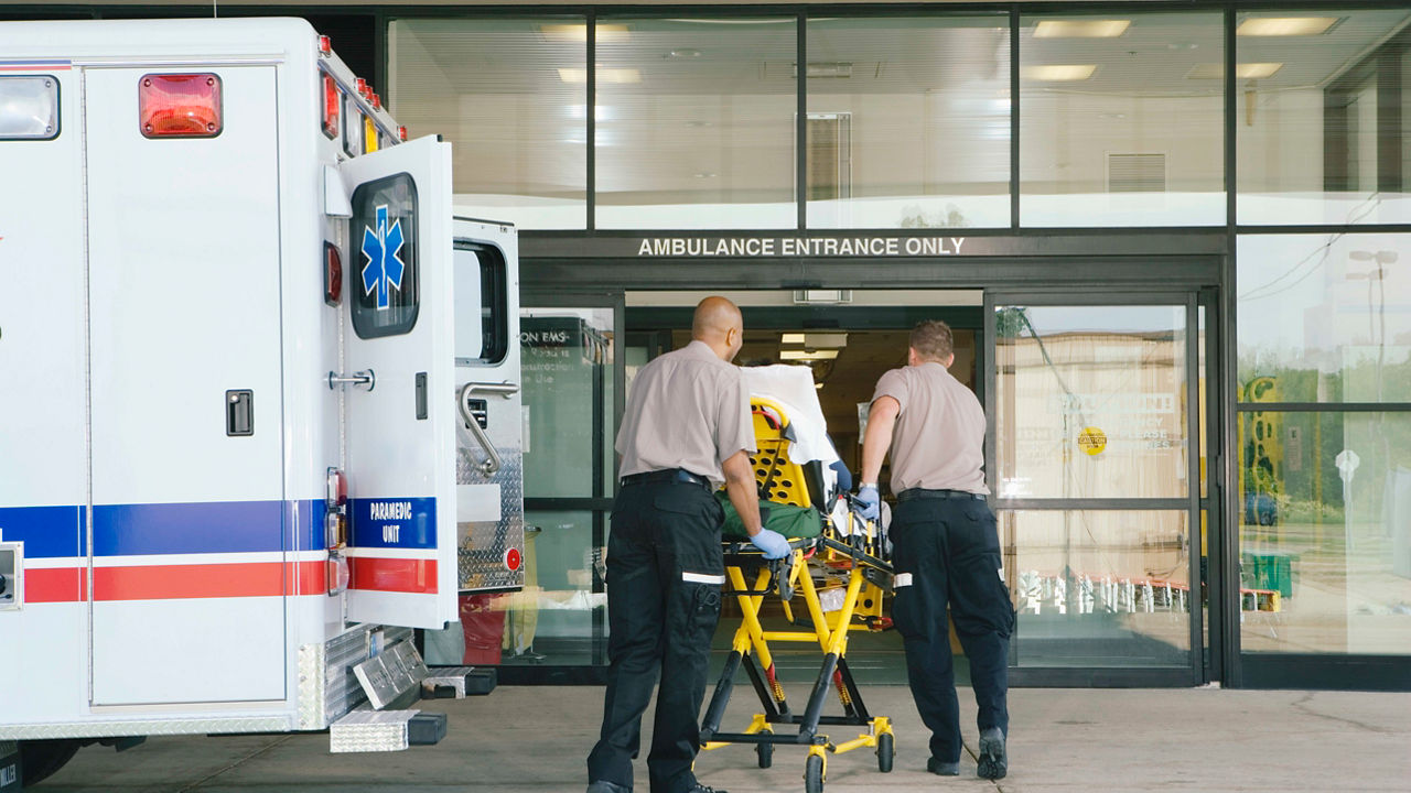 Two men standing next to an ambulance in front of a building.