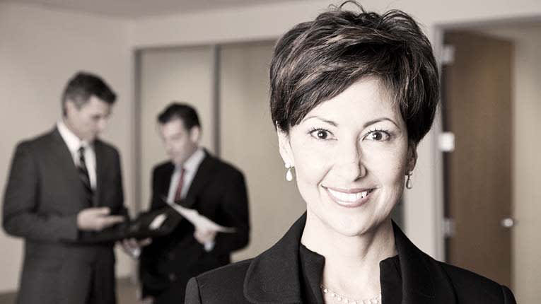 A woman in a business suit is smiling in front of a group of people.