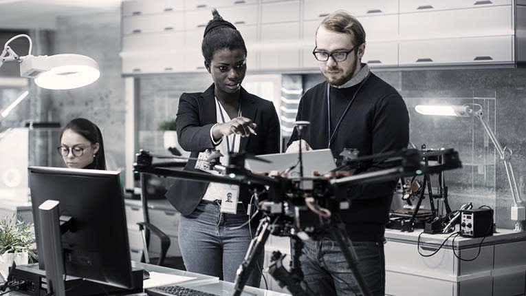 A group of people in an office looking at a drone.
