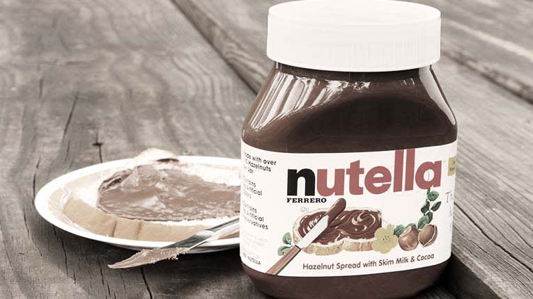 A bottle of nutella sits on a wooden table.