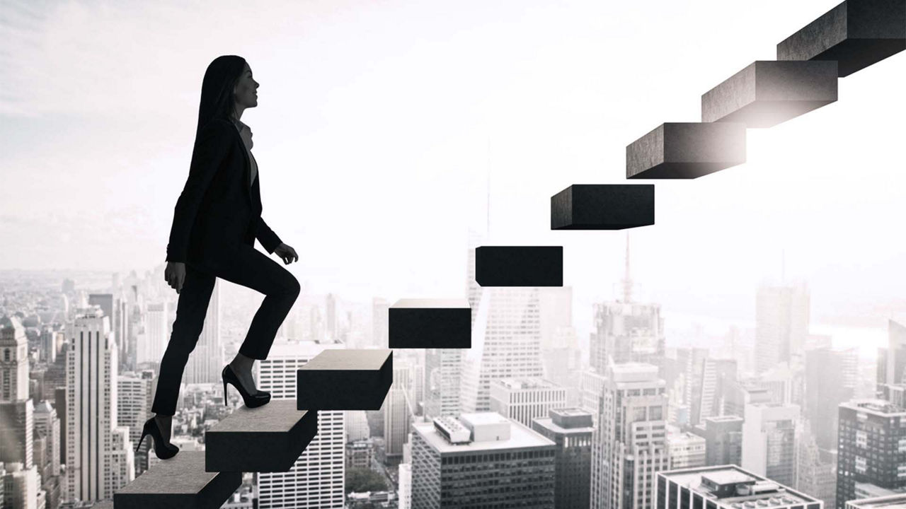 A business woman is walking up a set of stairs.