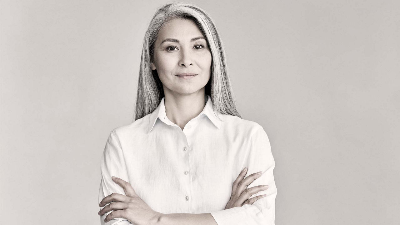 A woman in a white shirt posing with her arms crossed.