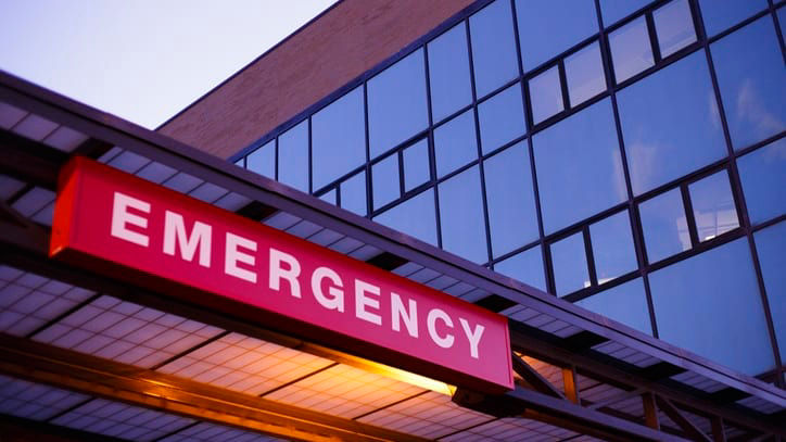 A hospital emergency sign is lit up at dusk.