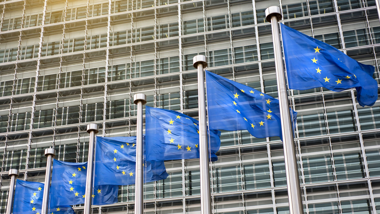 Eu flags flying in front of a building.