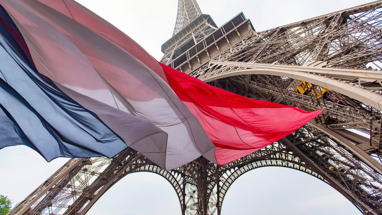 The eiffel tower with a french flag in front of it.