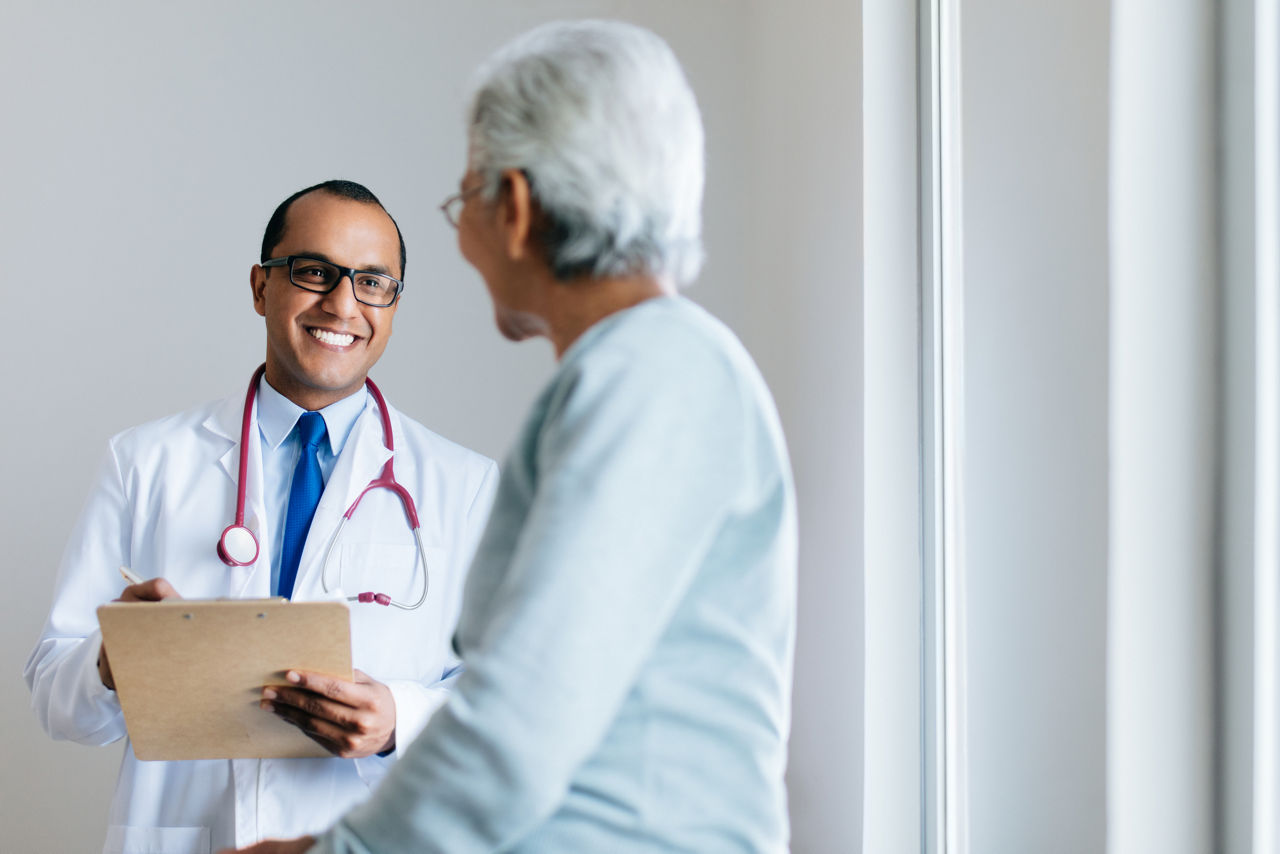 Hispanic doctor speaking to elderly woman