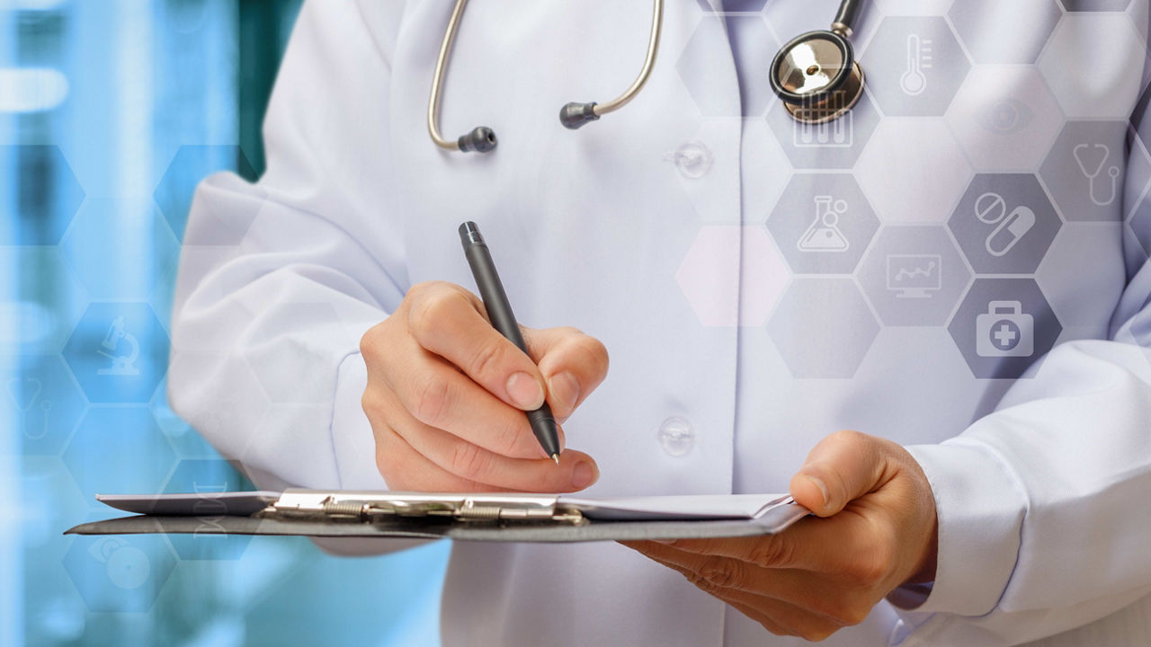 A female doctor is writing on a clipboard.
