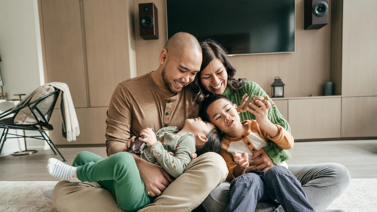 A family is sitting on the floor in front of a tv.