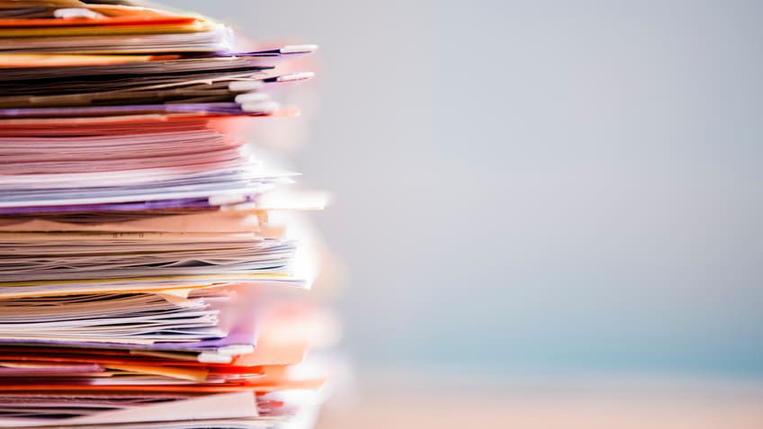 A stack of papers on top of a wooden table.