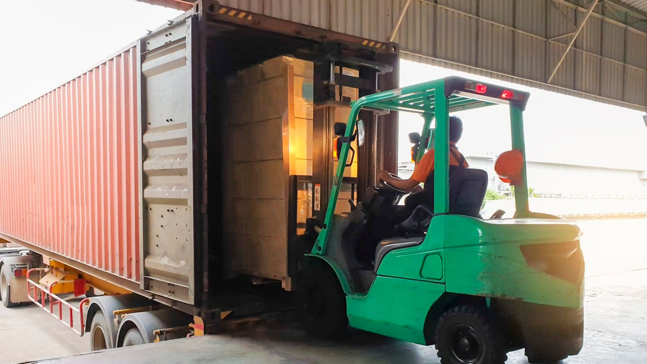 A forklift truck loading a container in a warehouse.