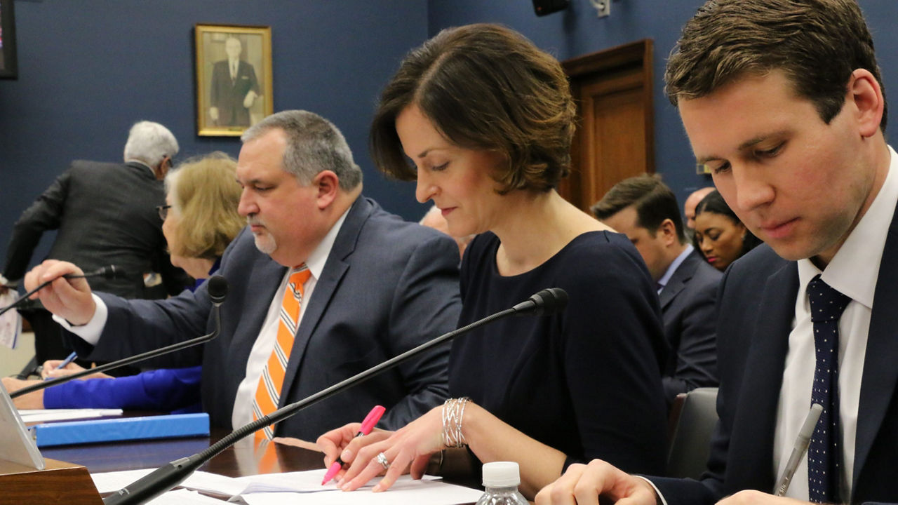 A group of people sitting at a table in front of a laptop.