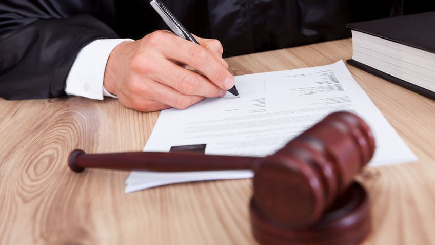 A judge signing a document with a gavel.