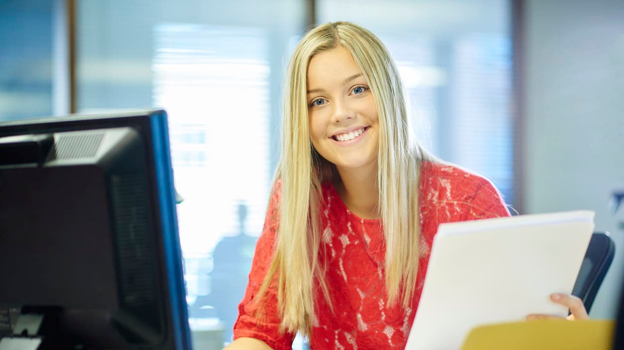 A smiling woman sitting at a desk in front of a computer.