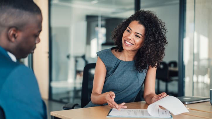 A business woman talking to a man in an office.