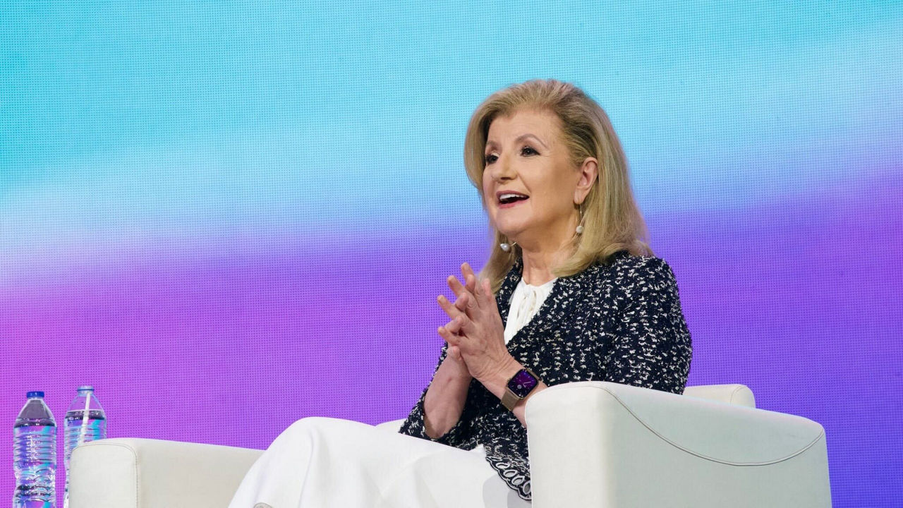 A woman sitting in a chair and talking on a stage.