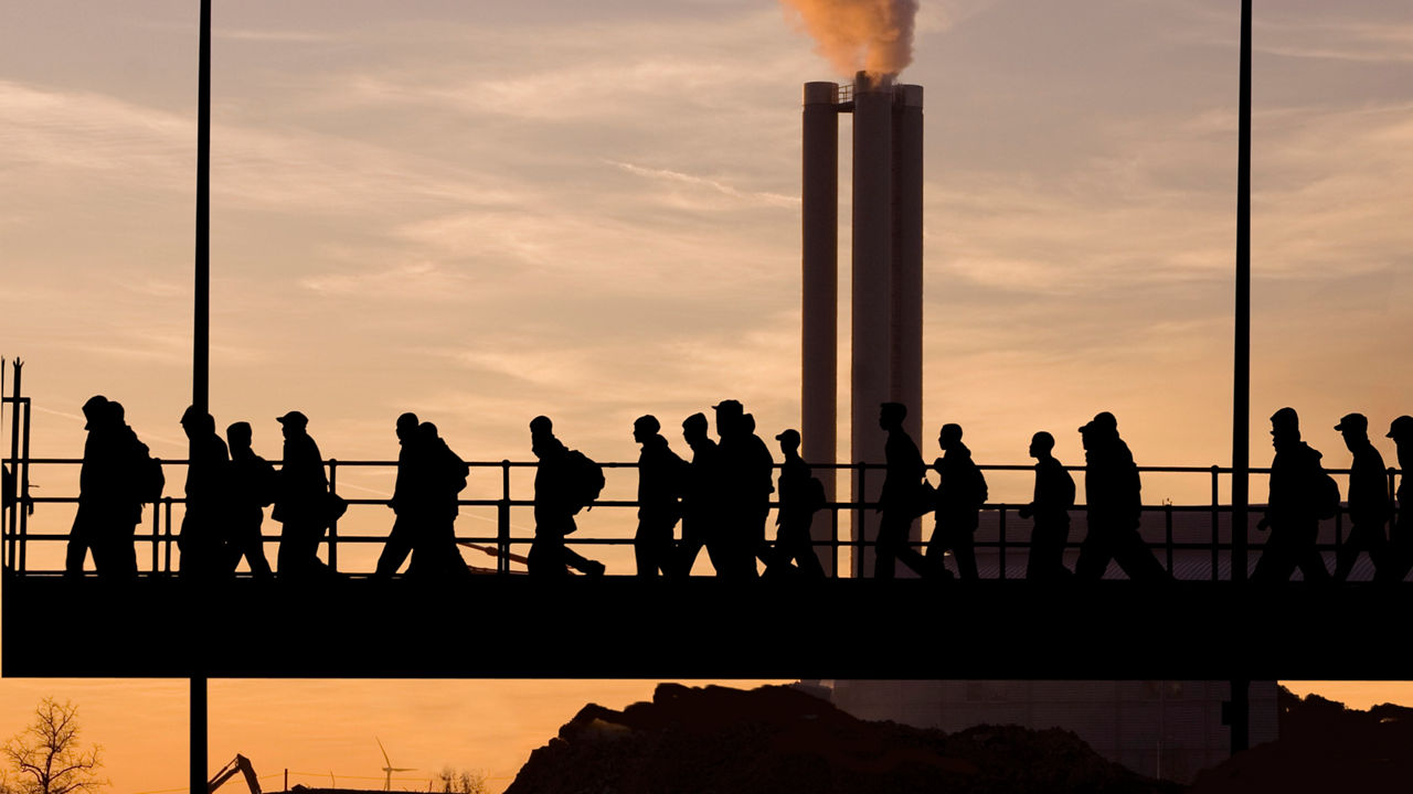 Silhouettes of people walking on a bridge at sunset.