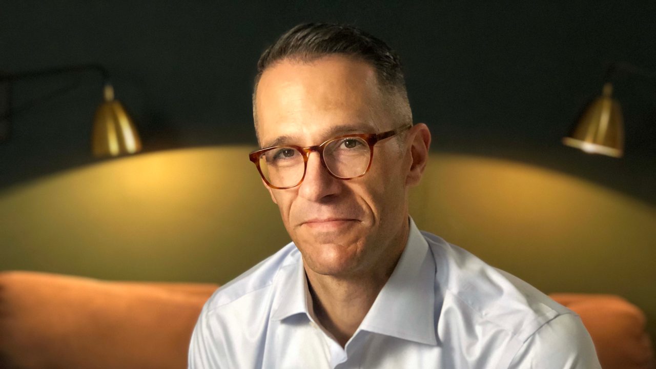 A man in glasses sitting on a couch.