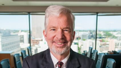 A man in a suit standing in a conference room.