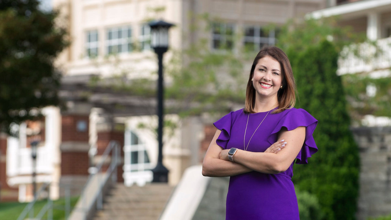 A woman in a purple dress standing in front of a building.