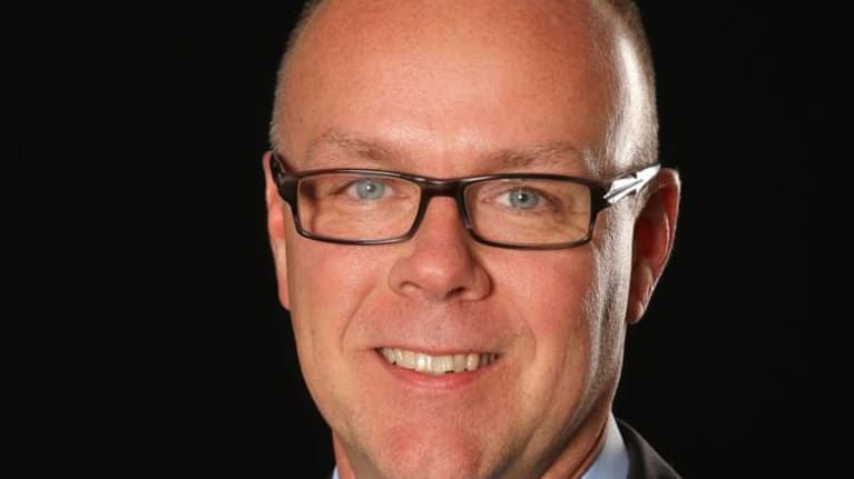 A man in a suit and tie smiles for the camera.