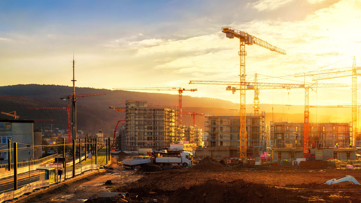 Construction cranes on a construction site at sunset.