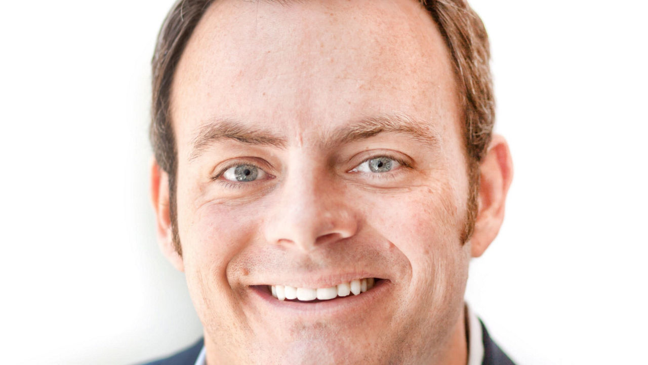 A man in a suit smiling for the camera.