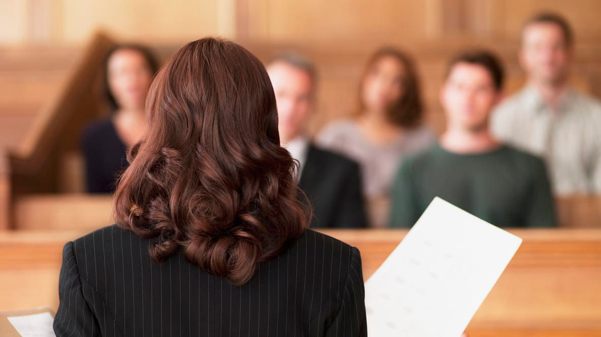 A woman in a suit standing in front of a courtroom.