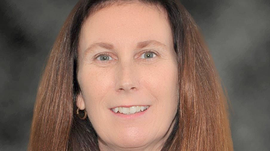 A woman in a business suit smiling for the camera.