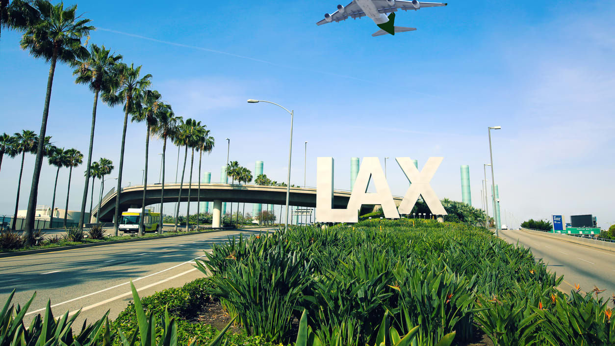 A plane is flying over a sign for lax.