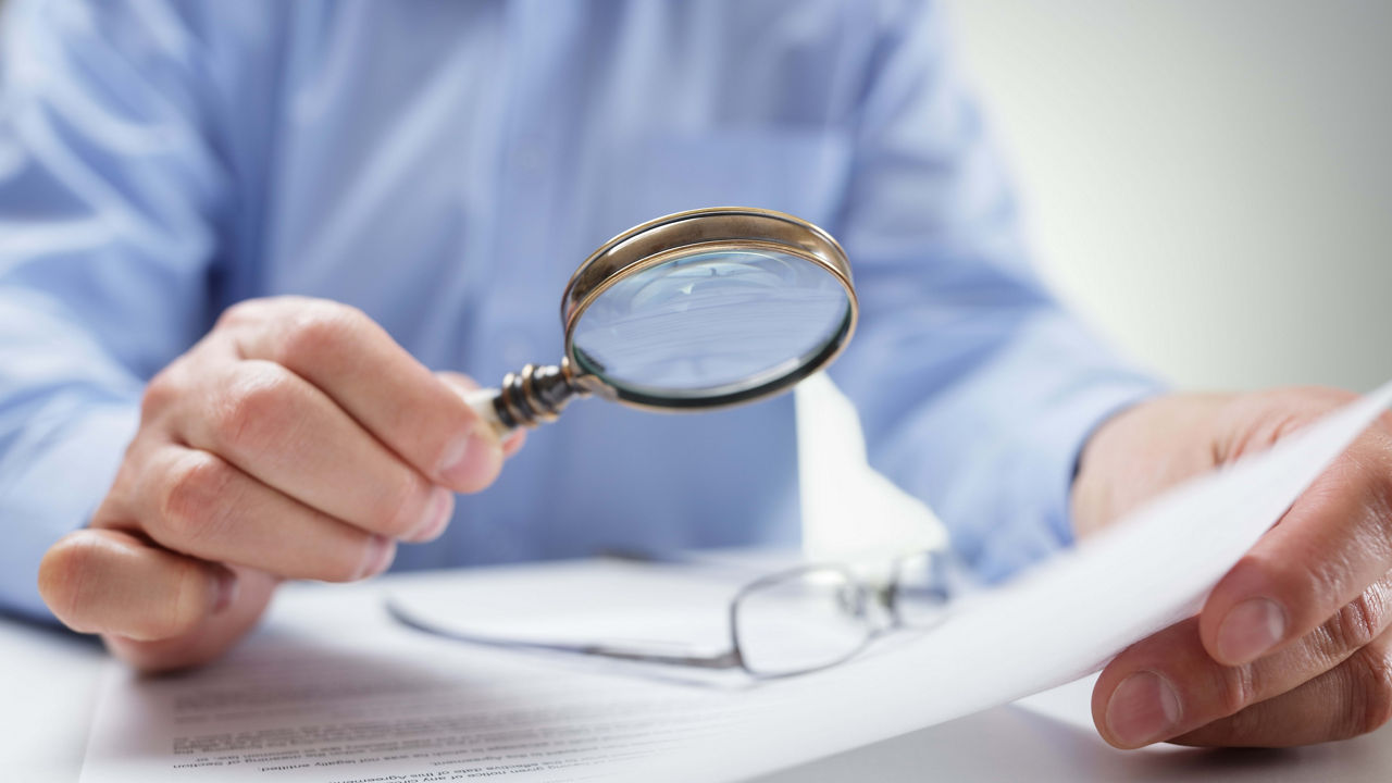 A man is looking through a magnifying glass at a piece of paper.