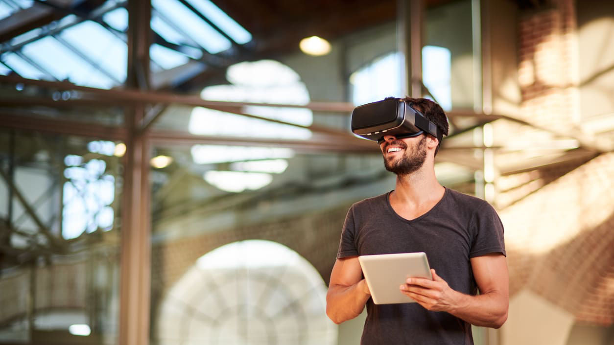 A man wearing a vr headset is standing in front of a building.